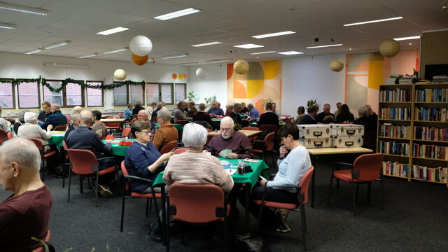 Volle zaal met spelers aan groene speeltafels