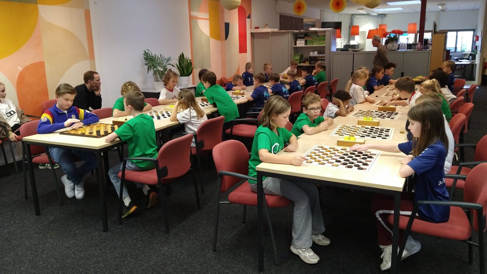 Kinderen in schoolshirts dammen aan lange tafels